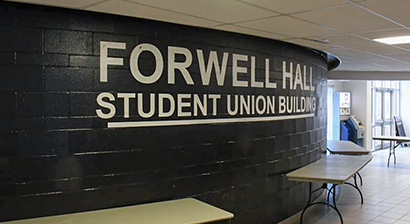 A black wall with text statting, Forwell Hall and Student Union Building. Tables are shown pushed against the wall.
