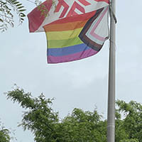 A Progress Pride flag and Fanshawe College flag hanging on flag poles.