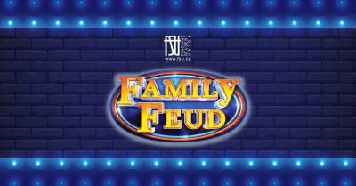 Bright yellow and orange Family Feud logo glowing against a dark blue brick wall with blue stage lights above and below.
