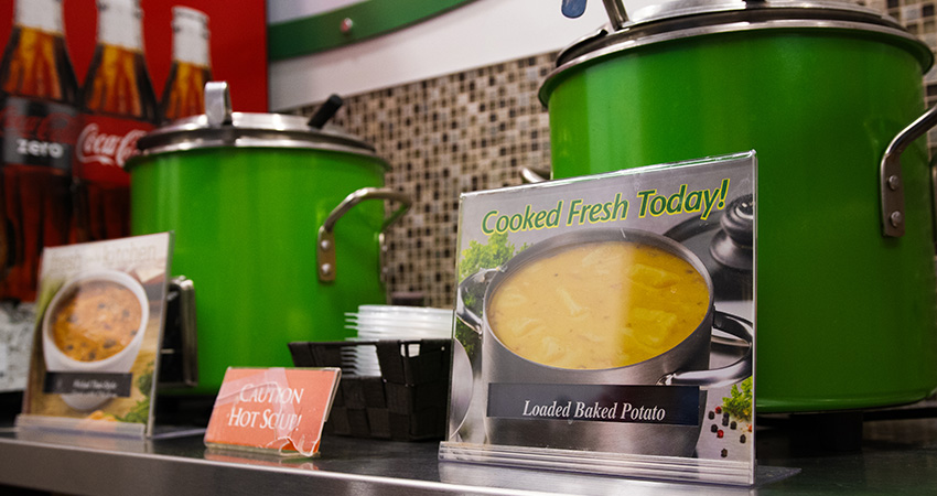 A photo of two kettles of soup with a sign that reads cooked fresh today.