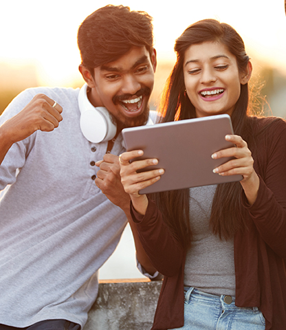 Two young people looking happy while viewing something on a tablet