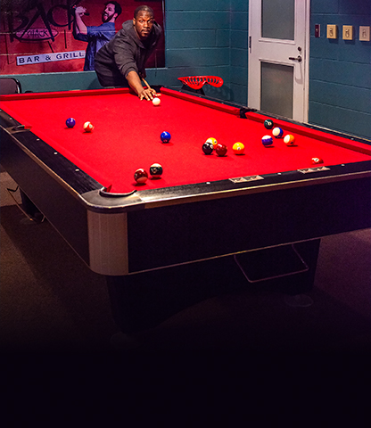 A person playing pool on a red pool table