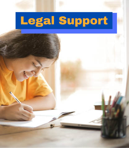 Young woman smiling while writing notes at a desk with a laptop, symbolizing legal support services.
