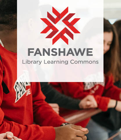 Students wearing red Fanshawe sweatshirts sit together in a library learning commons setting.