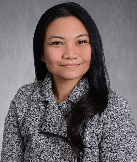 A headshot of Chary Vales in front of a grey background.