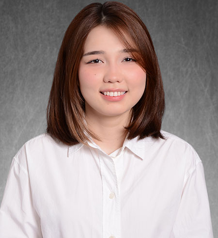 A headshot of Gulnaz Yekpinova smiling standing in front of a grey background.