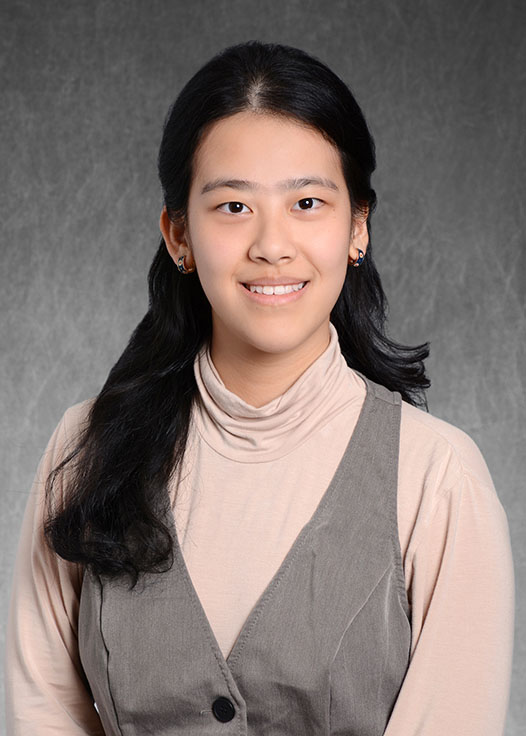 A headshot of Ruby Chen smiling standing in front of a grey background.